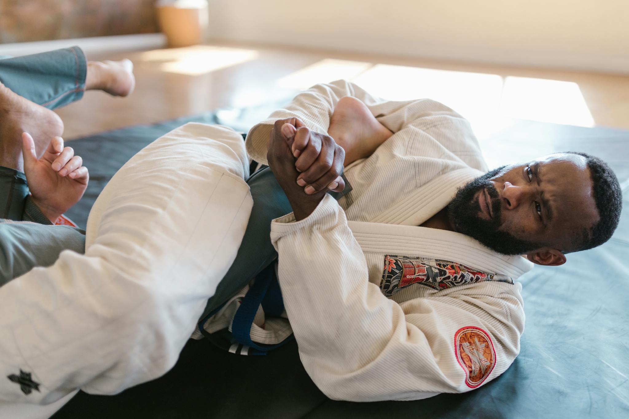 Martial artist practicing grappling in a gi during training session indoors.