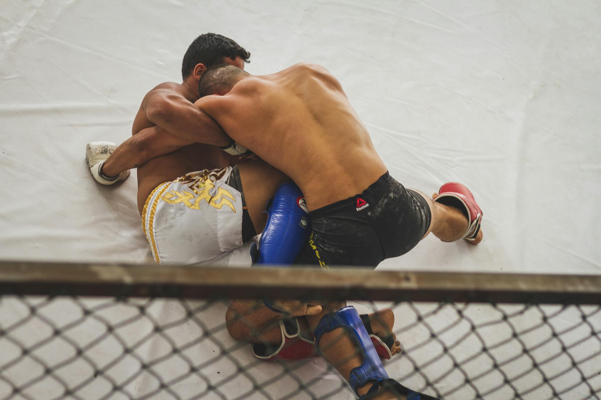 Two fighters engaged in a dynamic MMA grappling match inside a ring.