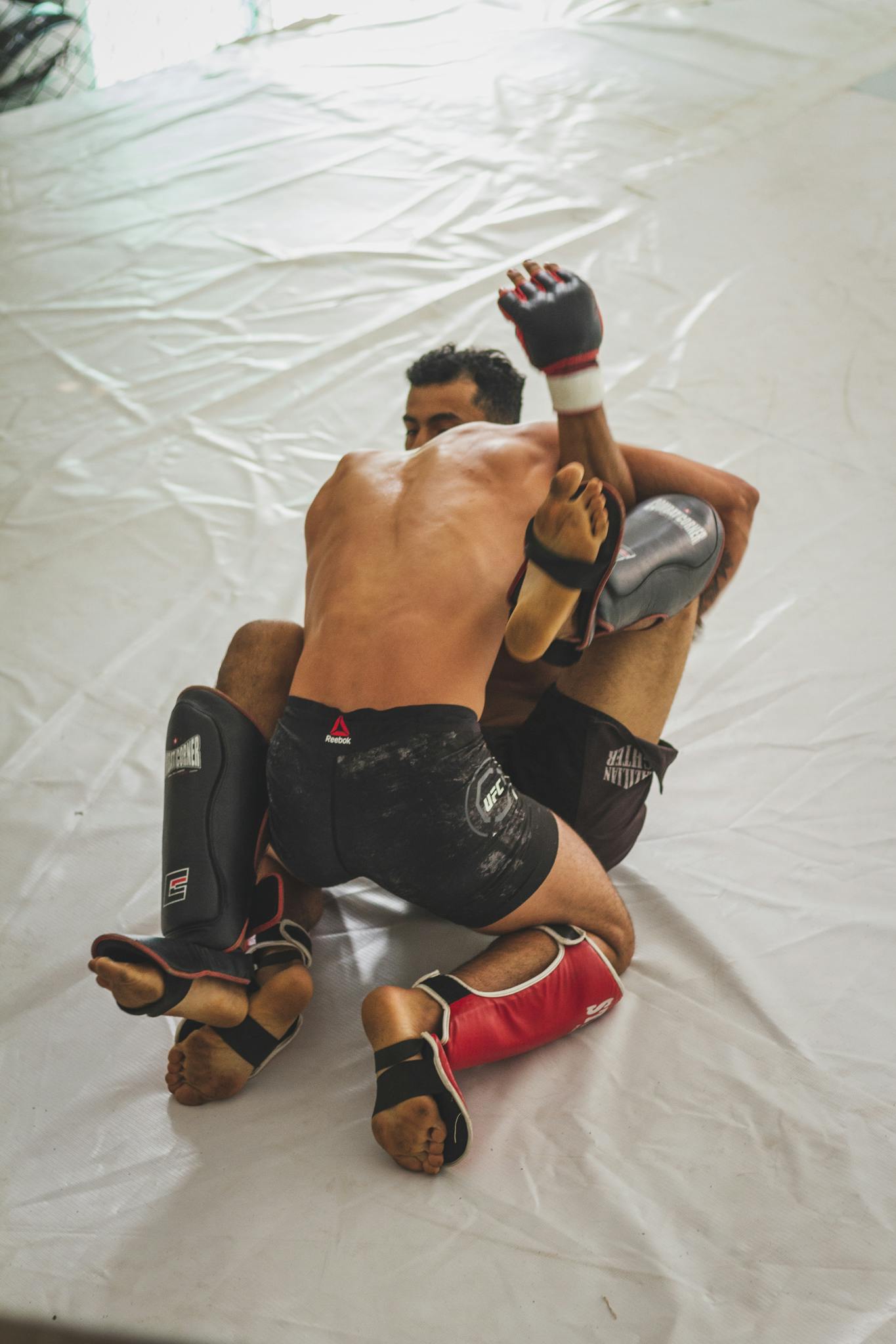 Two male MMA fighters engage in a dynamic sparring session, showcasing skill and technique.